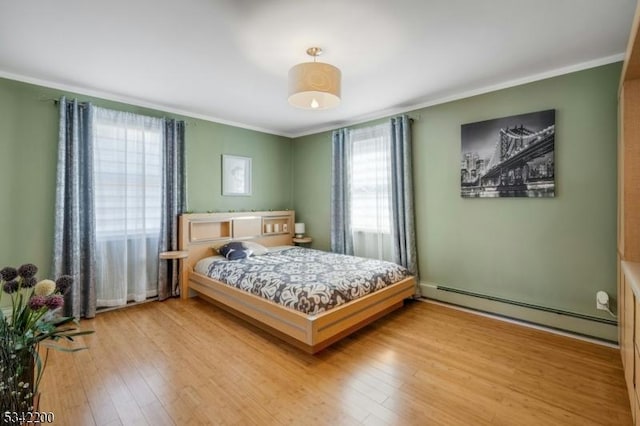 bedroom with a baseboard heating unit, wood-type flooring, and ornamental molding