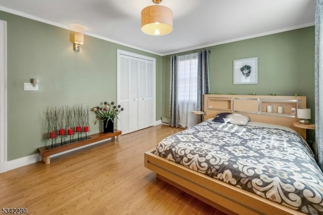 bedroom with baseboards, a closet, wood finished floors, and crown molding