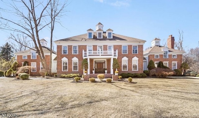 georgian-style home with brick siding and a balcony