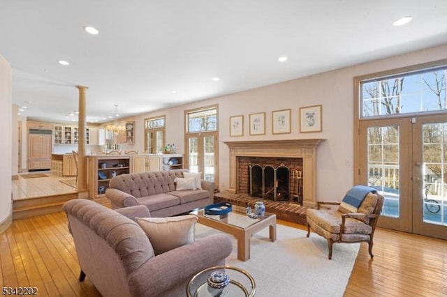 living area with a healthy amount of sunlight, light wood finished floors, and french doors