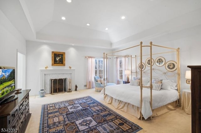 bedroom with a tray ceiling, light colored carpet, a fireplace, and recessed lighting