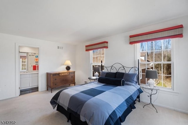 carpeted bedroom with multiple windows, visible vents, and ensuite bathroom