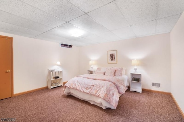 carpeted bedroom featuring a paneled ceiling, visible vents, and baseboards