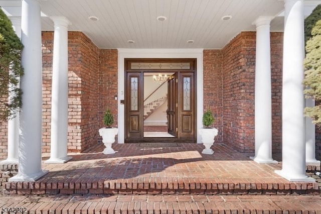 view of exterior entry with covered porch and brick siding