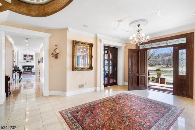 foyer featuring light tile patterned floors, a notable chandelier, baseboards, and crown molding