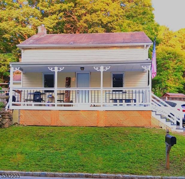 rear view of house with a lawn, a porch, and a chimney