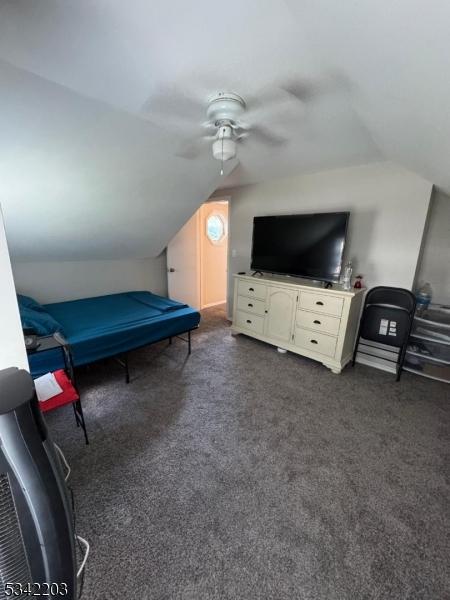 bedroom featuring ceiling fan, lofted ceiling, and dark colored carpet