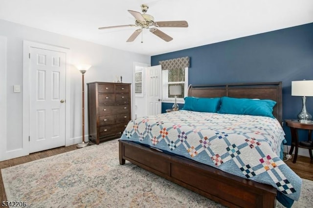 bedroom featuring a ceiling fan, baseboards, and wood finished floors