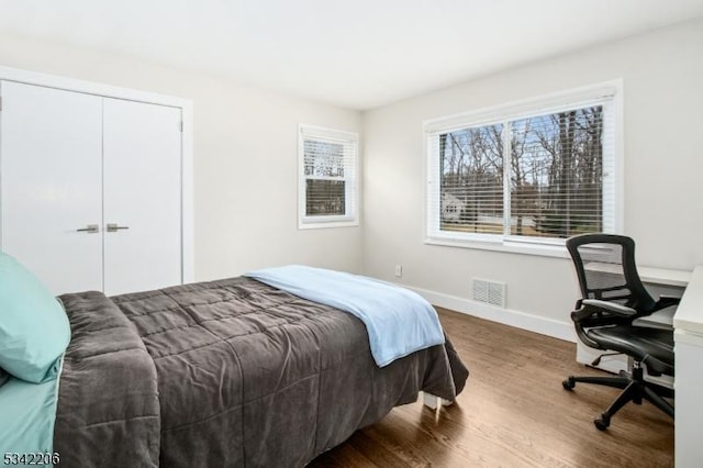 bedroom featuring a closet, wood finished floors, visible vents, and baseboards