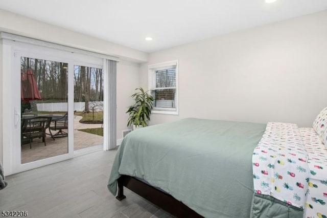 bedroom with access to outside, multiple windows, wood finished floors, and recessed lighting