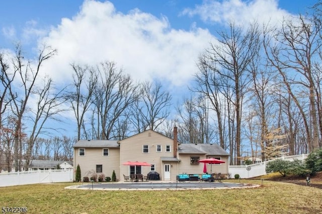 back of house with a patio area, a lawn, a chimney, and fence