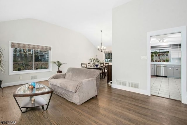 living room with vaulted ceiling, wood finished floors, visible vents, and a notable chandelier