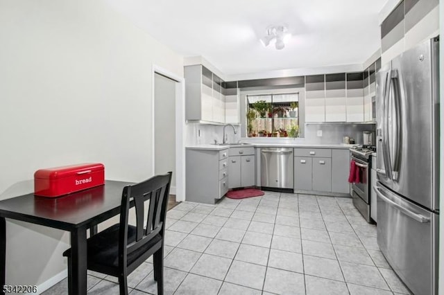 kitchen featuring tasteful backsplash, appliances with stainless steel finishes, light countertops, a sink, and light tile patterned flooring