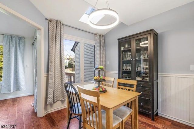 dining space featuring vaulted ceiling, wainscoting, and wood finished floors