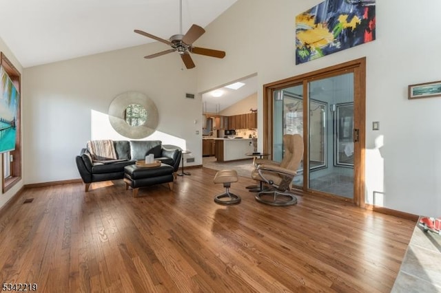 living room with baseboards, light wood-style floors, and high vaulted ceiling