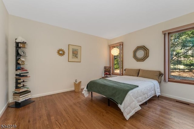 bedroom with visible vents, baseboards, and wood finished floors