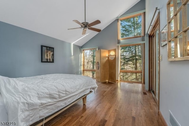 bedroom with visible vents, baseboards, wood finished floors, high vaulted ceiling, and a ceiling fan