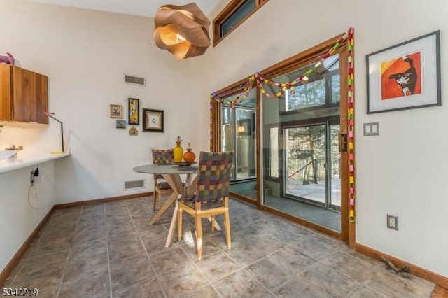 dining room featuring visible vents, baseboards, and a high ceiling