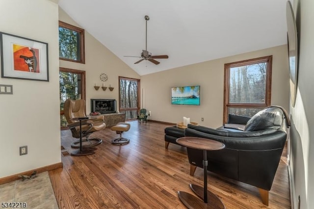 living area with baseboards, plenty of natural light, high vaulted ceiling, and wood finished floors