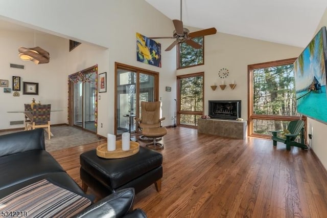 living area with a tiled fireplace, a healthy amount of sunlight, and wood finished floors