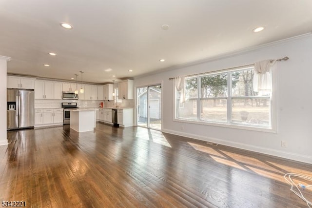 unfurnished living room featuring dark wood finished floors, a wealth of natural light, and baseboards