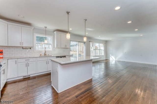 kitchen featuring tasteful backsplash, dark wood finished floors, a kitchen island, white cabinetry, and a sink