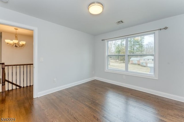 unfurnished room with a chandelier, dark wood-style flooring, visible vents, and baseboards