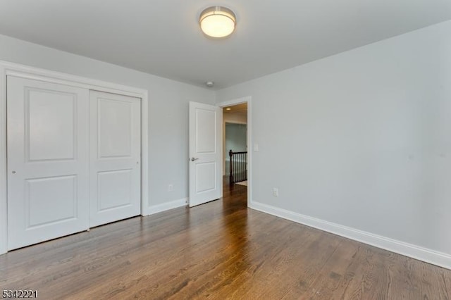 unfurnished bedroom with a closet, baseboards, and wood finished floors