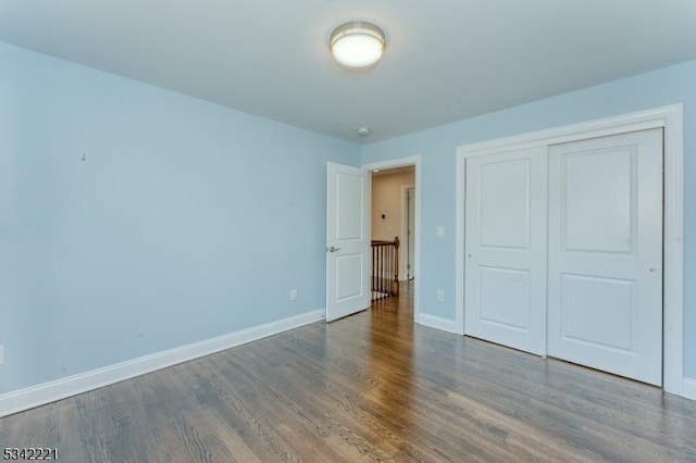 unfurnished bedroom featuring a closet, baseboards, and wood finished floors