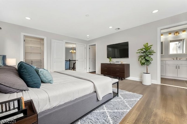 bedroom featuring connected bathroom, baseboards, wood finished floors, and recessed lighting