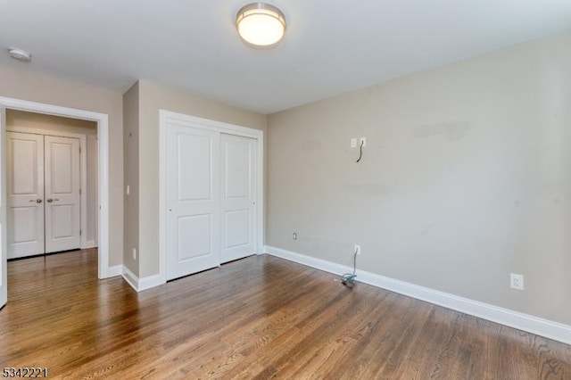 unfurnished bedroom featuring a closet, baseboards, and wood finished floors