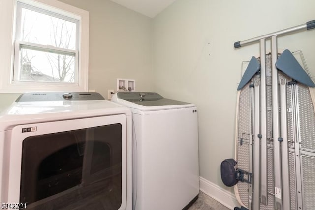 laundry area with laundry area, washer and clothes dryer, and baseboards