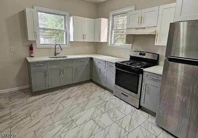 kitchen featuring marble finish floor, stainless steel appliances, gray cabinets, and under cabinet range hood