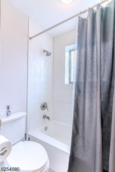 full bathroom with shower / bathtub combination with curtain and toilet