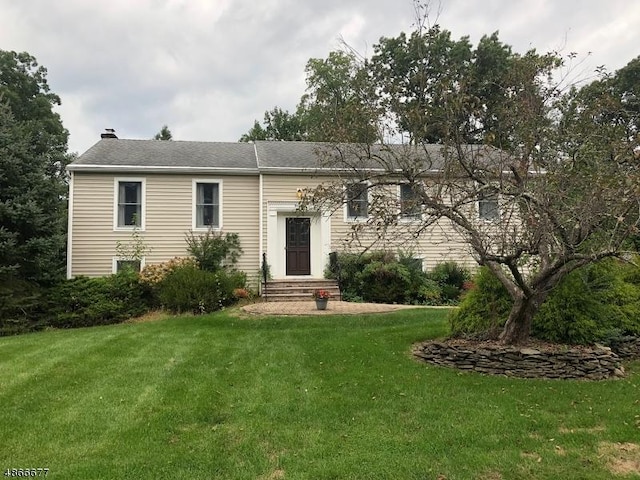 view of front facade with a front yard and a chimney