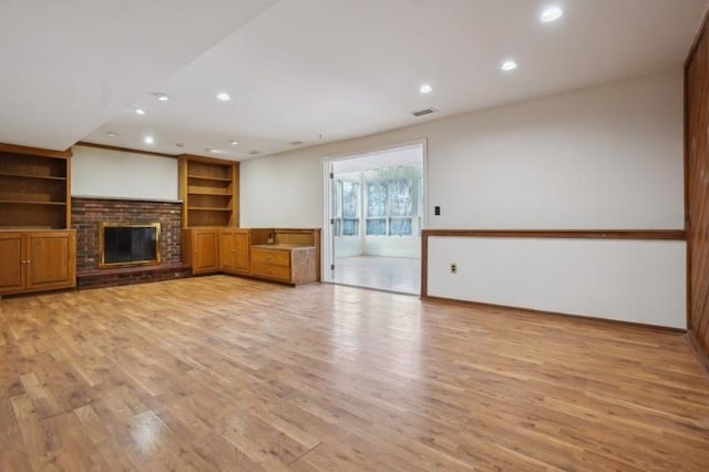 unfurnished living room with light wood finished floors, visible vents, recessed lighting, and a brick fireplace