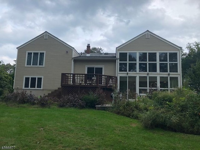 back of property featuring a deck, a yard, and a chimney