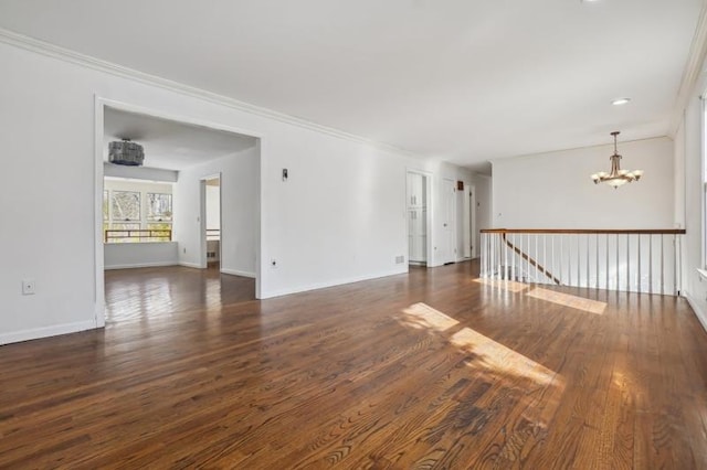 unfurnished room featuring a notable chandelier, crown molding, baseboards, and wood finished floors