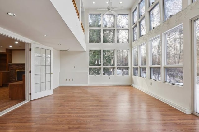 unfurnished sunroom featuring a brick fireplace and a ceiling fan