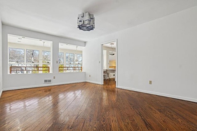 unfurnished room with visible vents, wood-type flooring, and baseboards