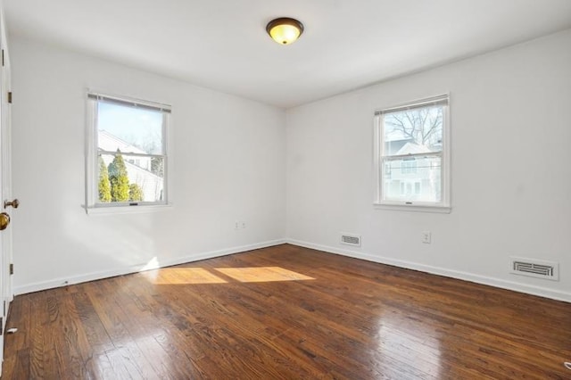 spare room featuring visible vents, wood-type flooring, and a healthy amount of sunlight