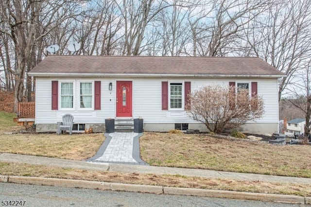 view of front of home with a shingled roof, entry steps, and a front lawn