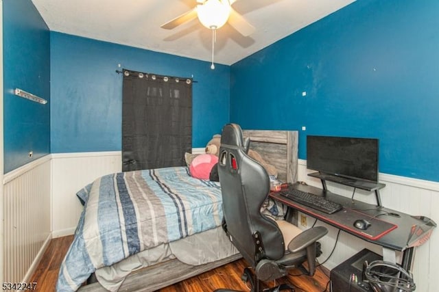 bedroom with a ceiling fan, a wainscoted wall, and wood finished floors