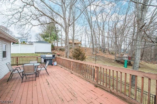 wooden terrace with area for grilling, a shed, an outdoor structure, and outdoor dining space