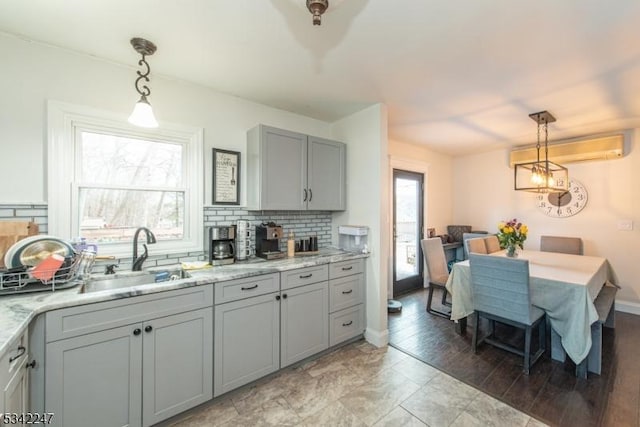 kitchen with hanging light fixtures, decorative backsplash, an AC wall unit, and gray cabinetry