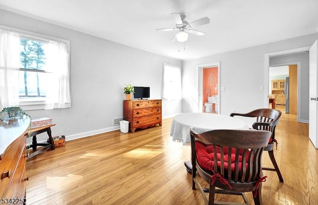 dining space with a ceiling fan, baseboards, and light wood finished floors