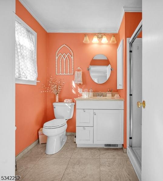 full bathroom featuring baseboards, toilet, ornamental molding, vanity, and a shower stall