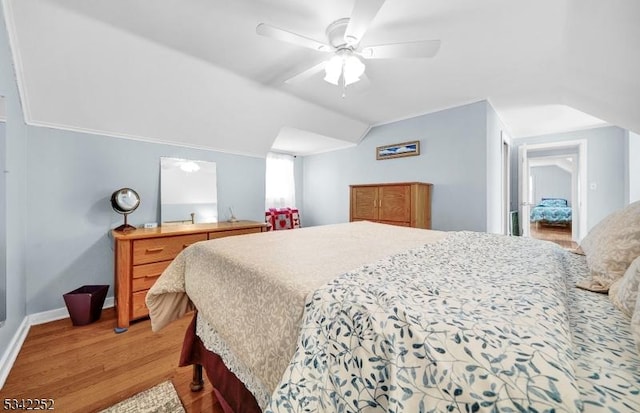 bedroom with lofted ceiling, light wood-type flooring, a ceiling fan, and baseboards