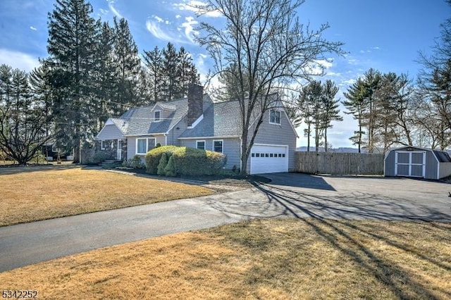 view of front of property with driveway, fence, an outdoor structure, a shed, and a front yard