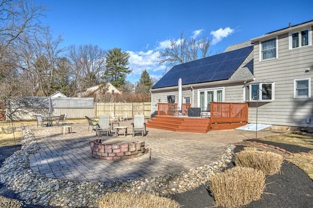 rear view of house with an outdoor fire pit, a patio area, fence, and a deck